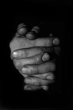 black and white photograph of two hands holding each other with their fingers folded in the middle