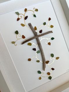 a cross made out of wood and leaves on a white card with gold chains hanging from it