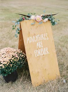 there is a sign that says adventures are forever next to some flowers in the grass