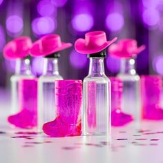 pink glass bottles with hats on them are lined up against a bright purple and white background