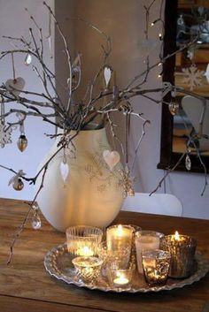 candles are lit in front of a vase with branches