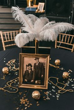 an old fashioned photo is on display in a gold frame with white feathers and other decorations