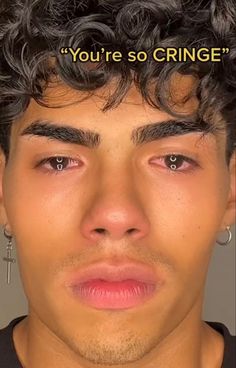 a young man with curly hair and piercings on his ears is looking at the camera