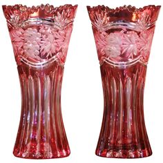 two pink vases sitting side by side on a white background, one has flowers in it