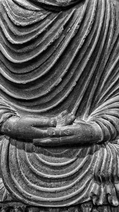 a black and white photo of a buddha statue with his hands folded out to the side