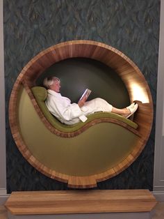 a man laying in a chair reading a book