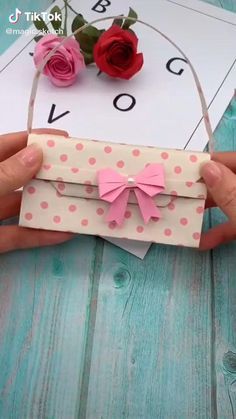 a person is holding a paper bag with flowers on it and a card in front of them