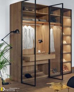 an open closet with clothes hanging on the shelves, and a chair next to it