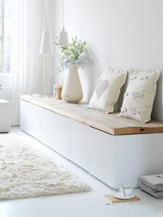 a living room with white furniture and rugs on the floor in front of a window