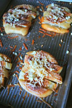 small pizzas with cheese and sauce sitting on a baking sheet lined with grated cheese