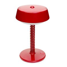 a red table lamp sitting on top of a white floor