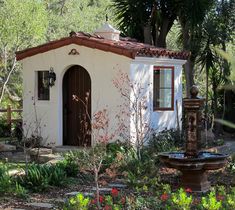 a small white building with a fountain in front of it