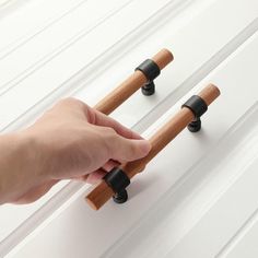 a hand is holding the handles to two wooden poles with black knobs on them