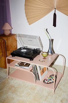 a pink table with record players and an umbrella in the corner on top of it