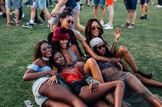 group of young women sitting on the grass at an outdoor music festival smiling and having fun