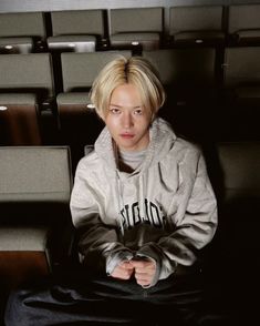 a woman sitting on top of a chair in front of rows of empty theater seats