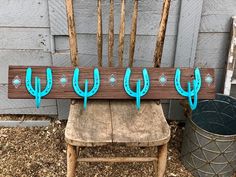 a wooden chair sitting in front of a wall with three blue cactus hooks on it