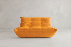 an orange couch sitting on top of a white floor