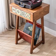 a record player sitting on top of a wooden table next to a book case and magazine rack