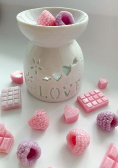 pink and purple candies in a white bowl with love written on the side next to them