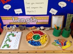 a wooden table topped with lots of toys and writing on the wall next to a ruler