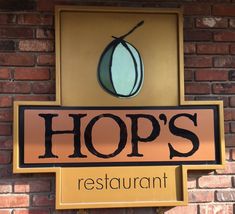 a restaurant sign hanging on the side of a brick building that says hop's