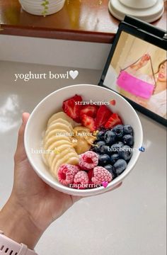 a person holding a bowl of fruit with the words yogurt bowl on it