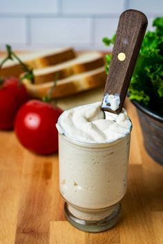 a glass filled with whipped cream sitting on top of a wooden table next to tomatoes