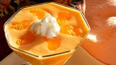 a dessert with oranges and whipped cream in a glass dish on a plate next to an orange slice