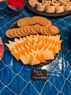 an assortment of cheeses and crackers on a blue tablecloth with other snacks