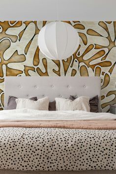 a large bed sitting under a lamp on top of a wooden headboard