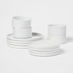 stack of white cups and saucers sitting next to each other on a white surface