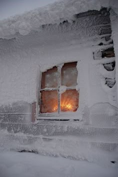 a window is covered in snow and lit by the light of a candle on it