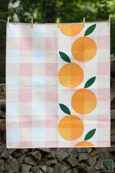 an orange quilt hanging on a clothes line next to some logs and trees in the background