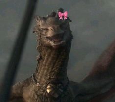 a close up of a dragon with a pink bow on its head