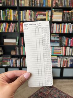 a person holding up a book in front of a bookshelf filled with books