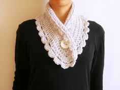 a woman wearing a white crochet scarf with a button on the front and neck