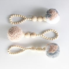 three wooden beaded objects are arranged on a white surface, including beads and balls