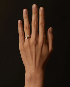 a woman's hand with a diamond ring on her left hand, against a black background