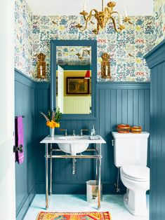 a bathroom with blue walls and floral wallpaper on the walls, along with a white toilet and sink