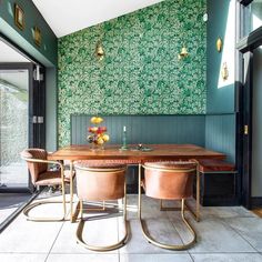 a dining room with green wallpaper and leather chairs