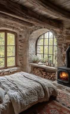 a bedroom with a bed and a fireplace in the corner next to two large windows