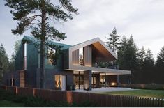 a modern house in the middle of a wooded area with grass and trees around it