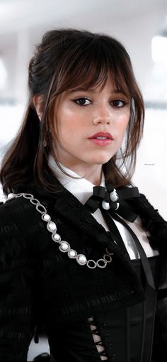 a woman wearing a black and white outfit with pearls on the collar, neckline