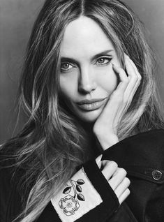 a black and white photo of a woman with her hand on her face, looking at the camera