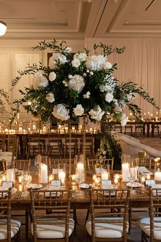 a large centerpiece with flowers and candles is displayed on a long wooden table surrounded by chairs