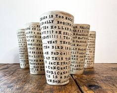 four shot glasses sitting on top of a wooden table with words printed all over them