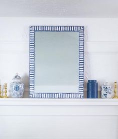 a white mantle with blue vases and a mirror on the mantel above it