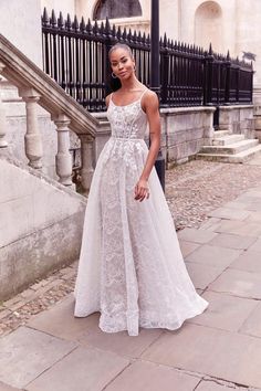 a woman in a white dress standing on the sidewalk