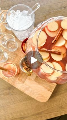 an apple cider with cinnamons and apples in it on a wooden cutting board